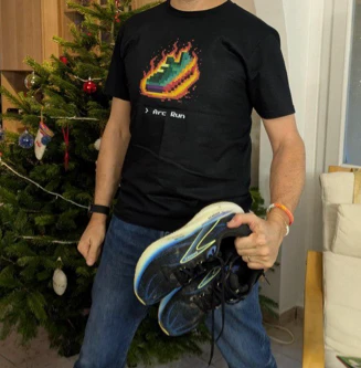 Um corredor com a t-shirt preta do Arc Run, a segurar sapatilhas